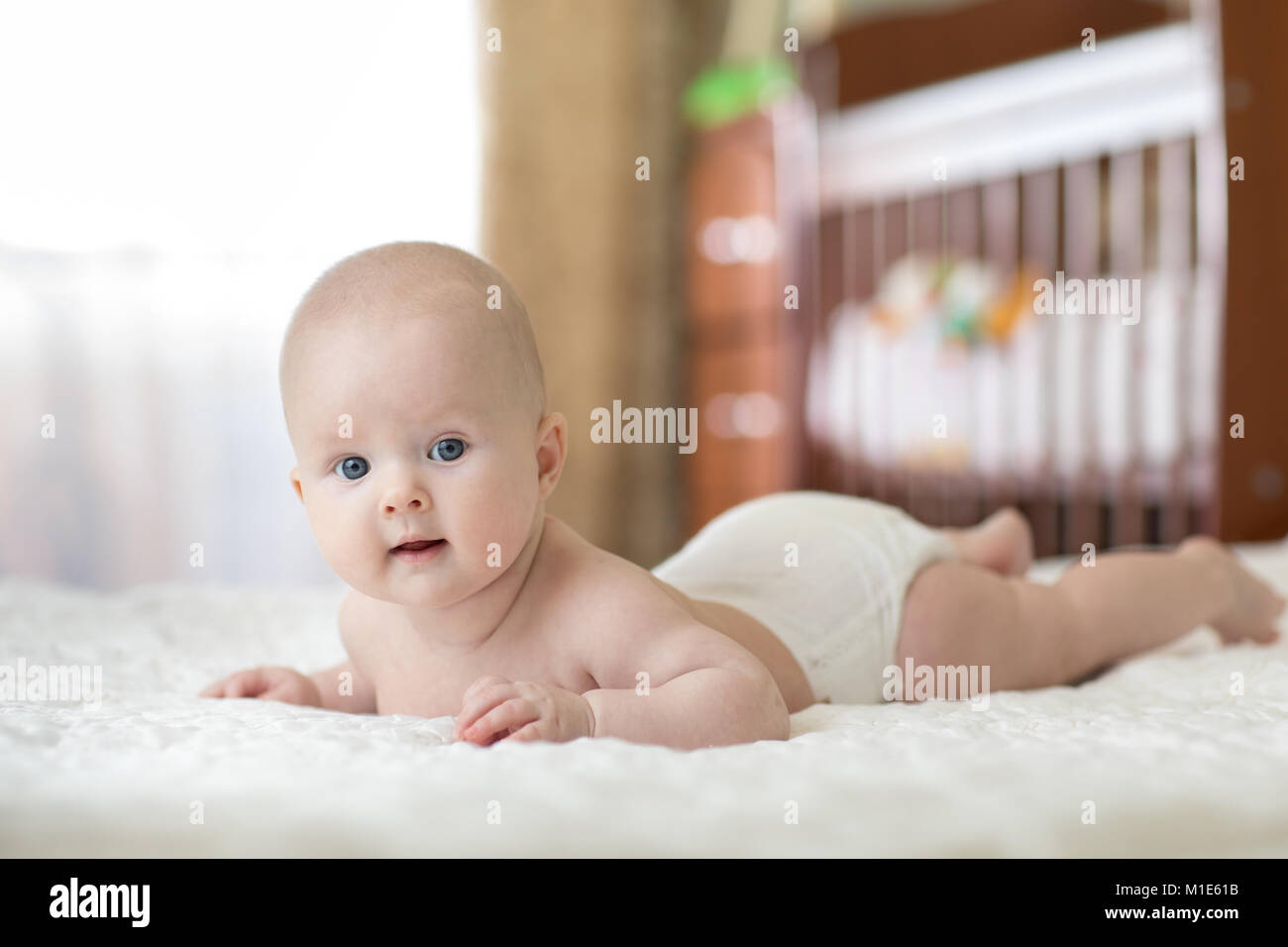 Portrait of a four months old baby on the bed in nursery room Stock