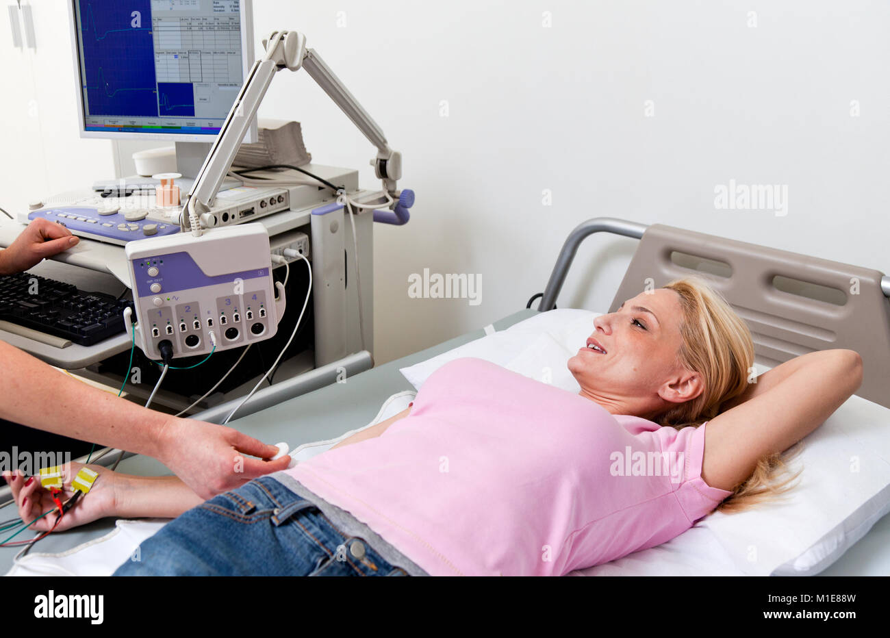 woman lying in hospital bed, being examed with electromyography machine Stock Photo