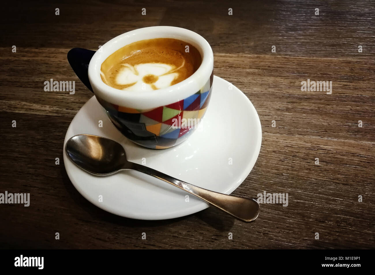 Espresso cup with milk foam flower, on wooden table. Italian coffee ...