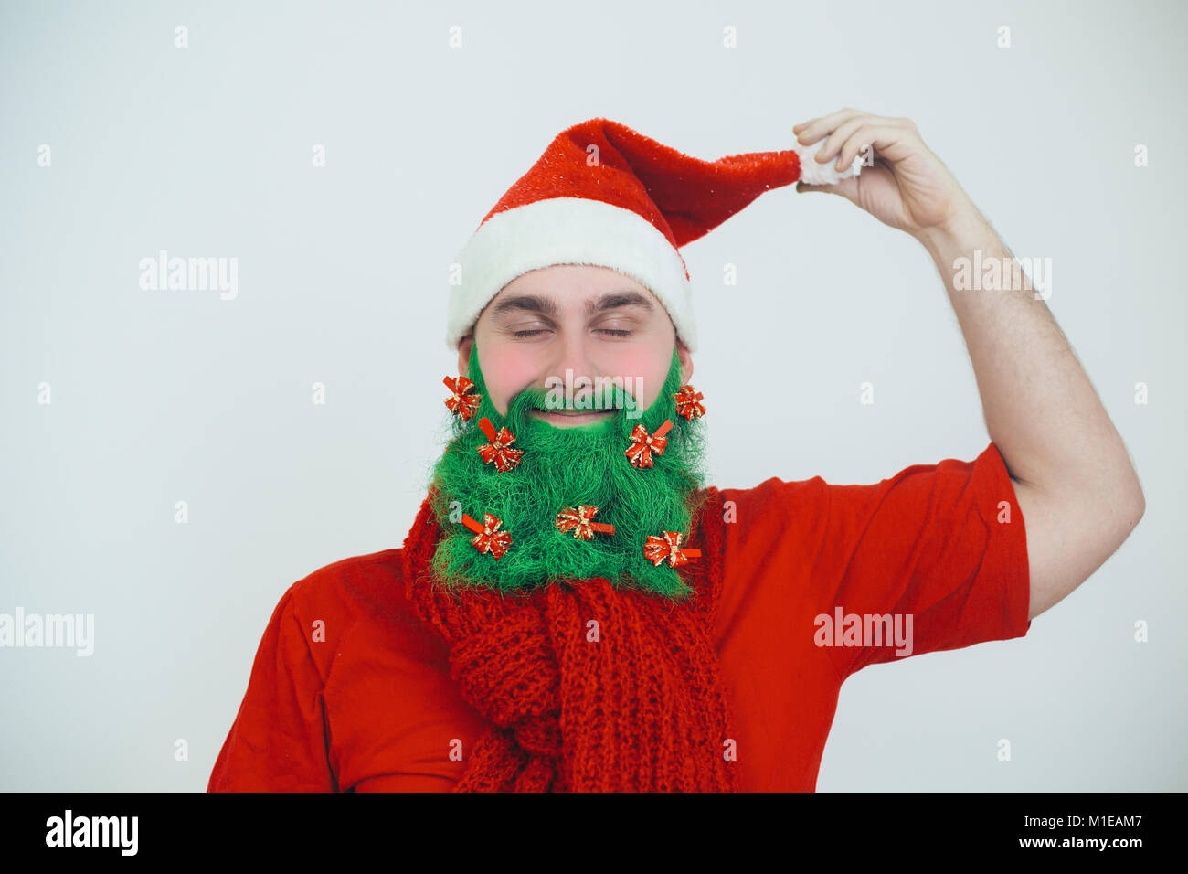 Santa Clause in red clothes with green beard decorated with red bows like a christmas tree Stock Photo