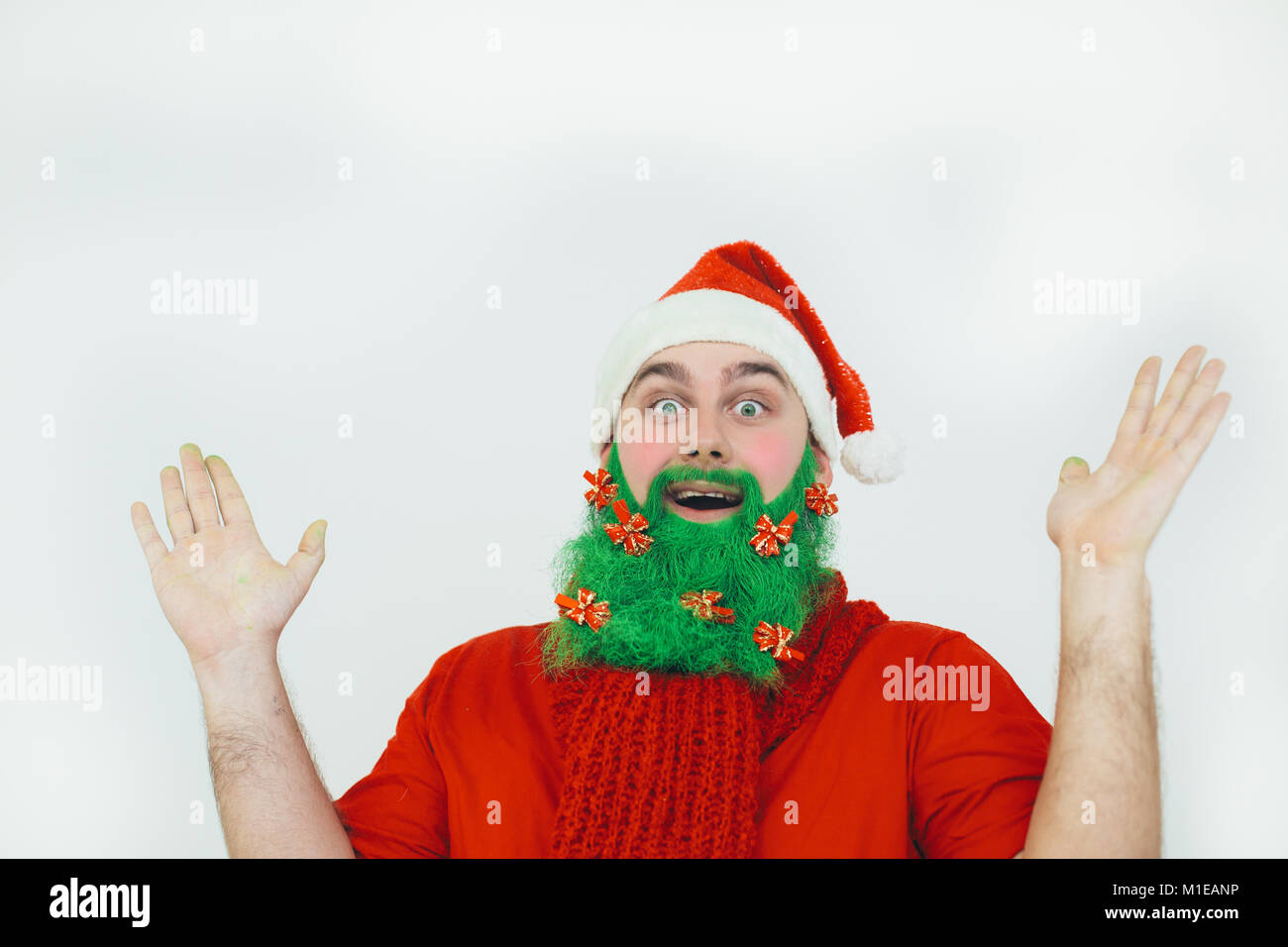 Santa Clause in red clothes with green beard decorated with red bows wonders of something Stock Photo