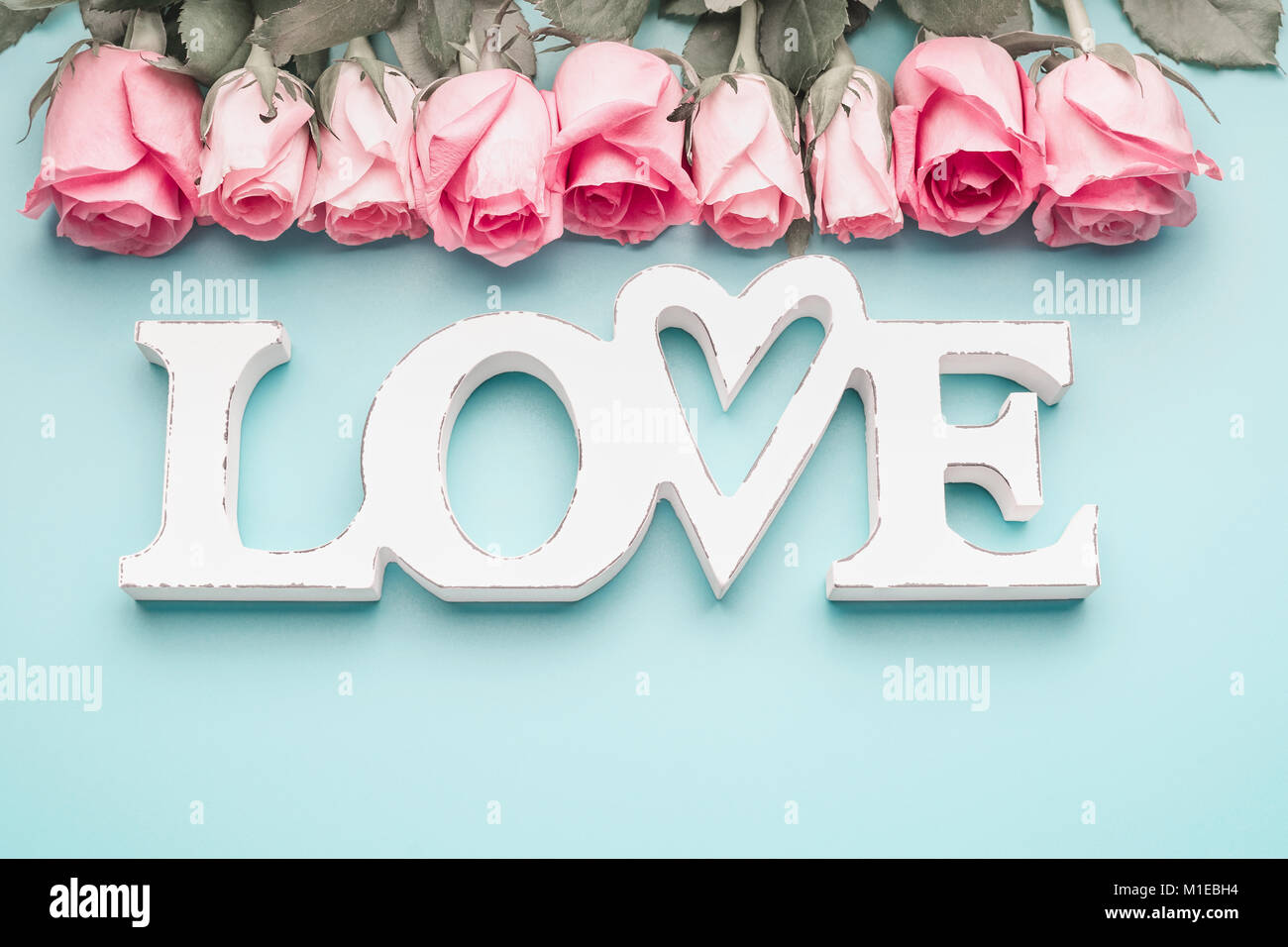 White Word Love With Pastel Pink Roses On Turquoise Blue Background