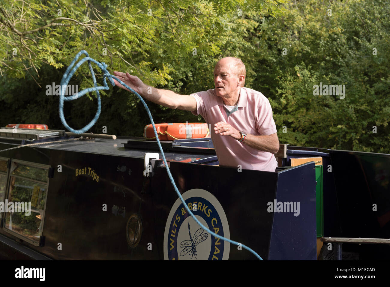 Holidaymaker throwing a mooring line to shore from a narrowboat Stock Photo