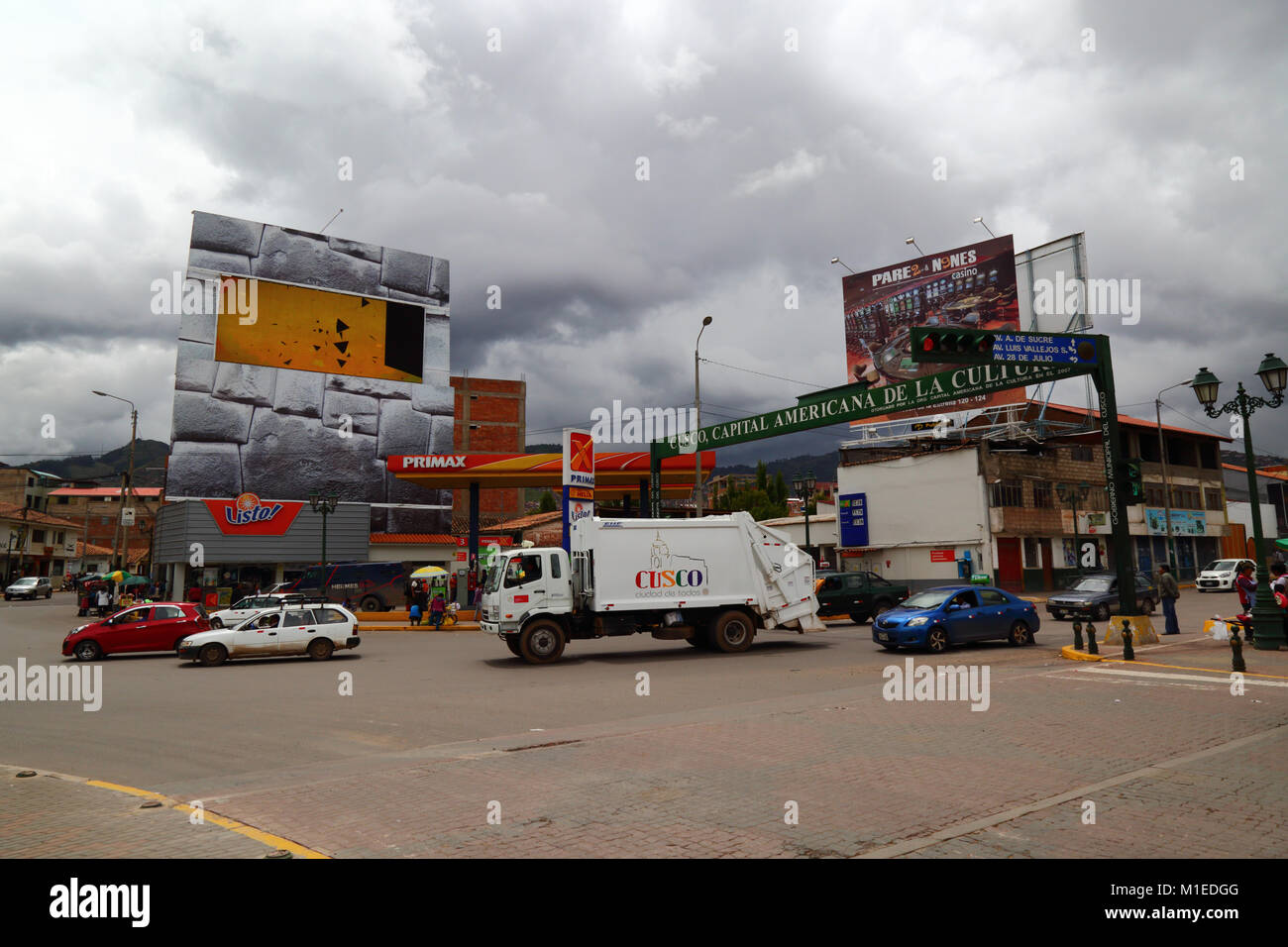 Dustcart / garbage truck passing digital advertising screen set in giant Inca wall design hoarding, Cusco, Peru Stock Photo