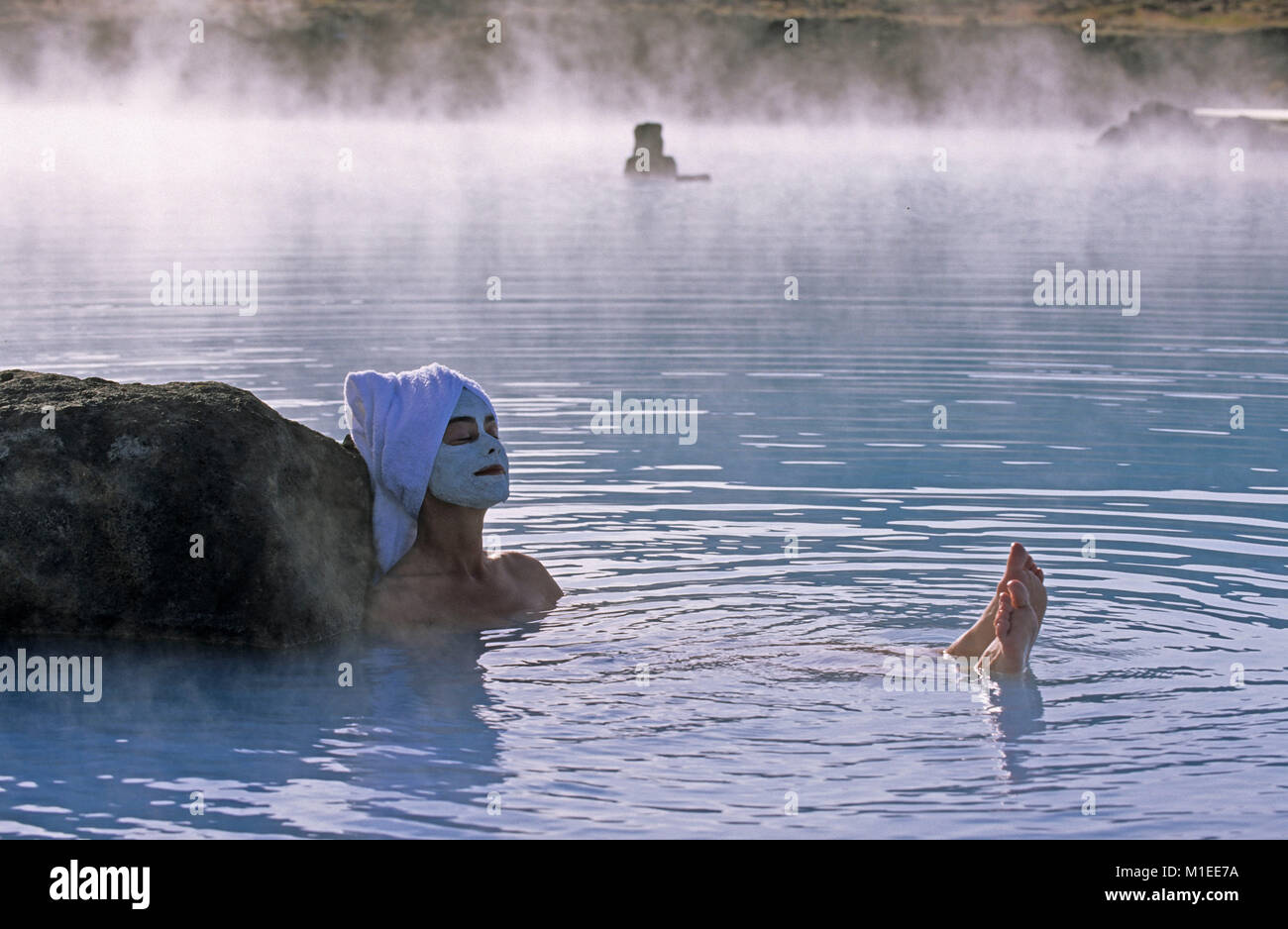 Iceland. Myvatn. Myvatn Nature Baths. Woman wearing beauty mask, towel on head, sitting in geothermal spa. Stock Photo