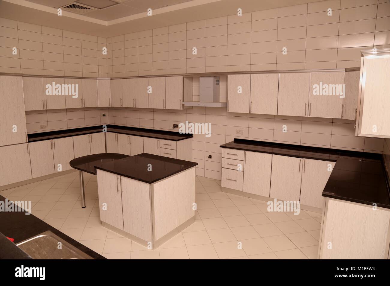 Modern Kitchen with White Color Kitchen Cabinet Wall and Base Units, Cooker Hood and Dining Table Stock Photo