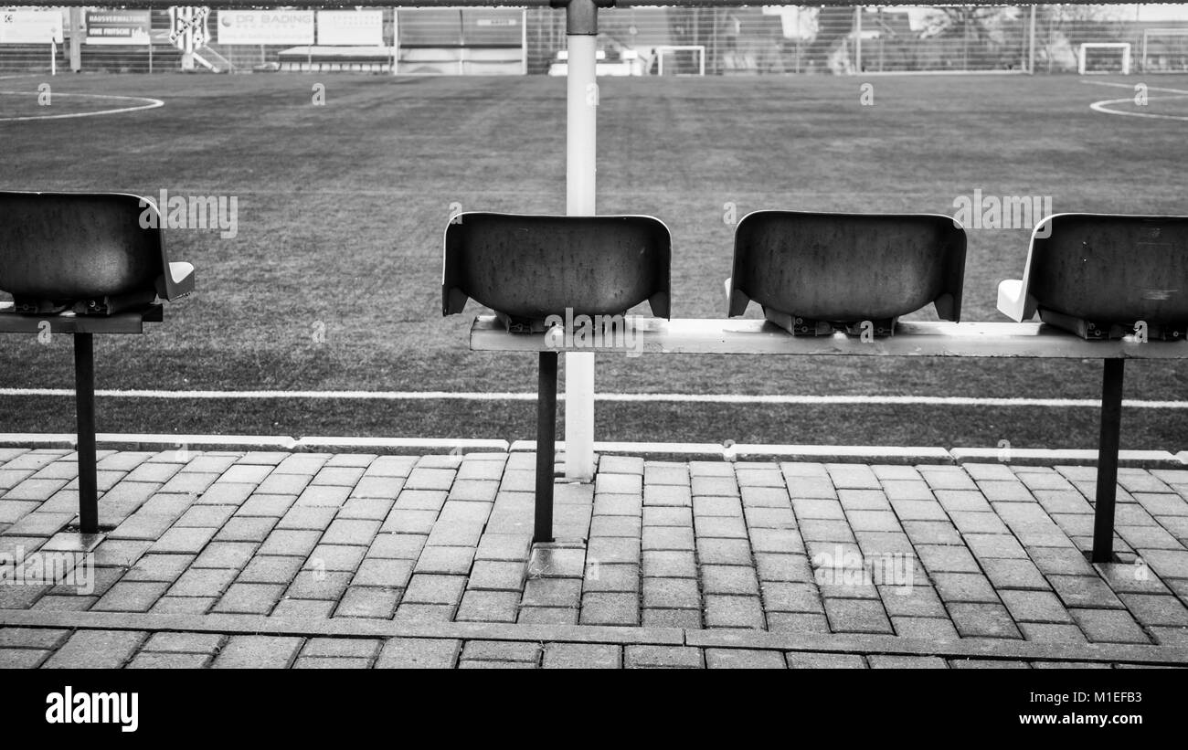 Emtpy soccer field and chairs/seats in a small community. Rainy and grey weather. Bad mood. (black and white) Stock Photo