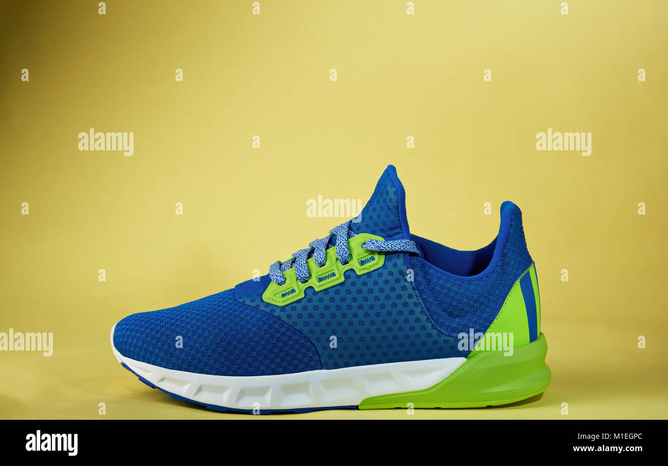One colorful new sneaker shoe isolated on yellow background. Stock Photo