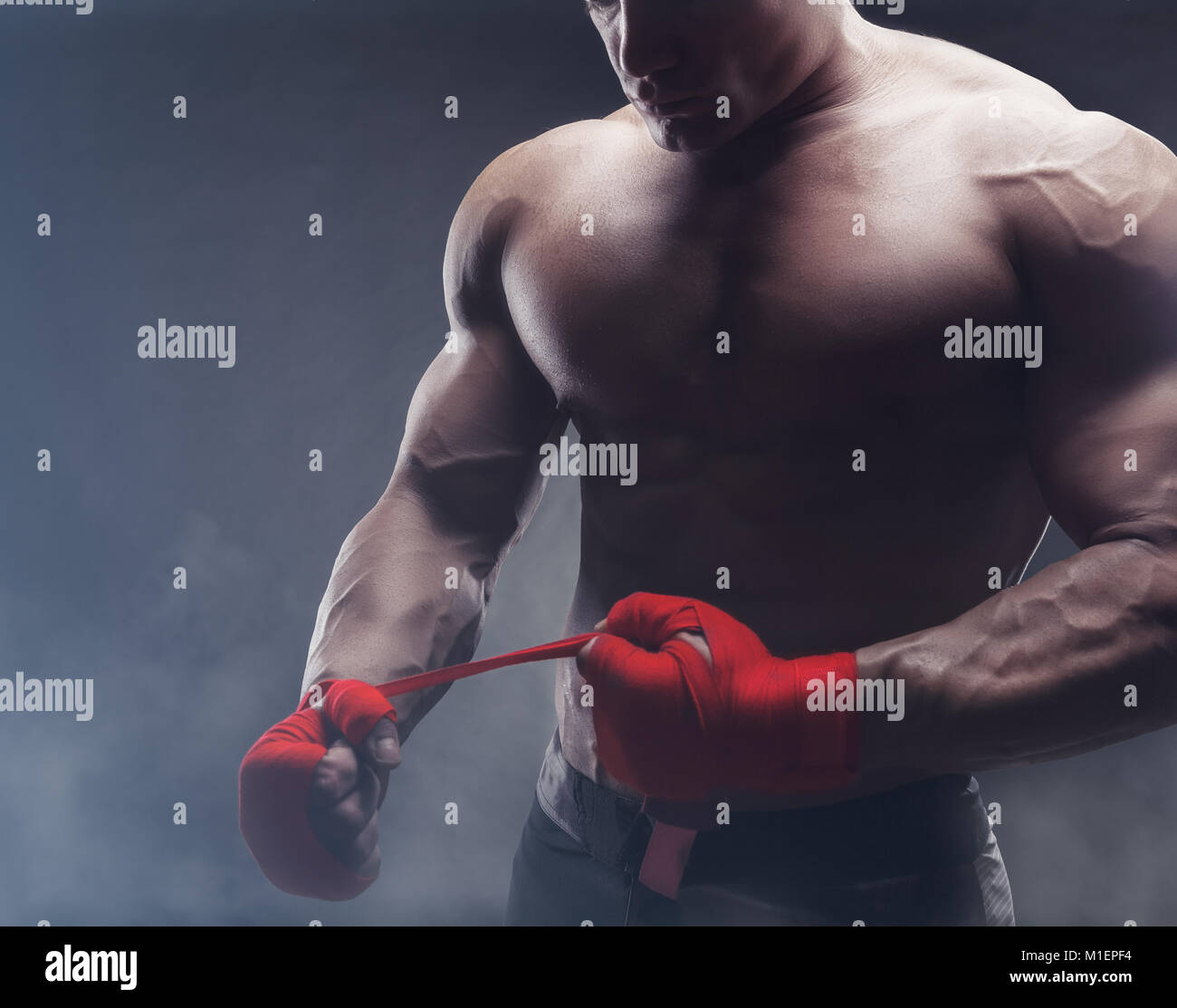 Close-up of a strong boxer putting on red straps and getting ready to fight Stock Photo