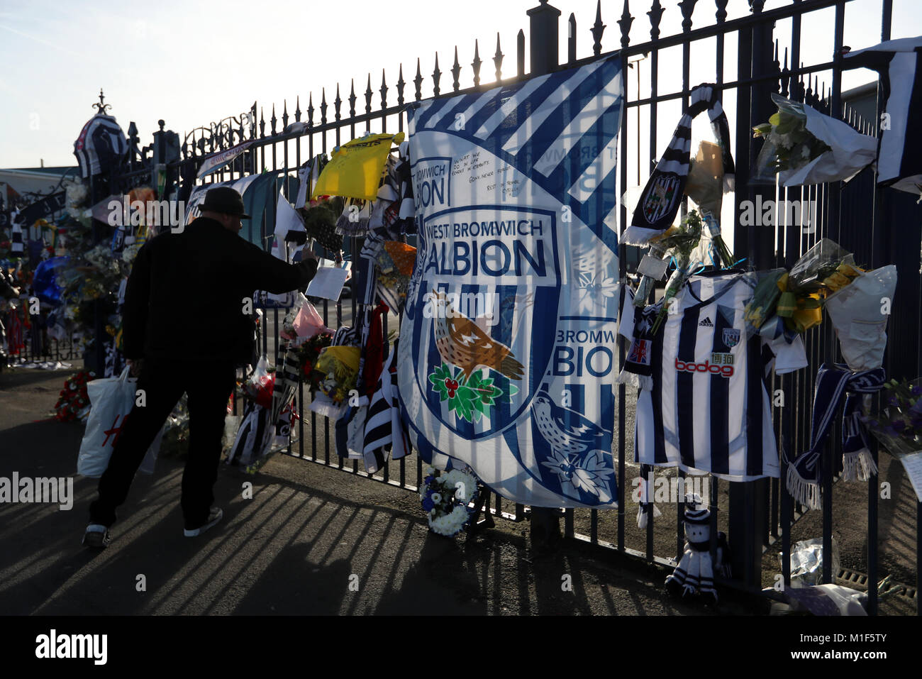 A fan takes a photgraph of tributes laid on the gates during the memorial service for Cyrille Regis at The Hawthorns, West Bromwich. Stock Photo