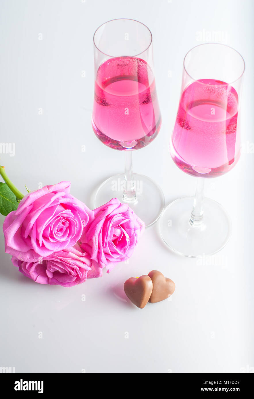 Chocolate hearts, rose flowers and two glasses of pink champagne. white background. selective focus. Stock Photo