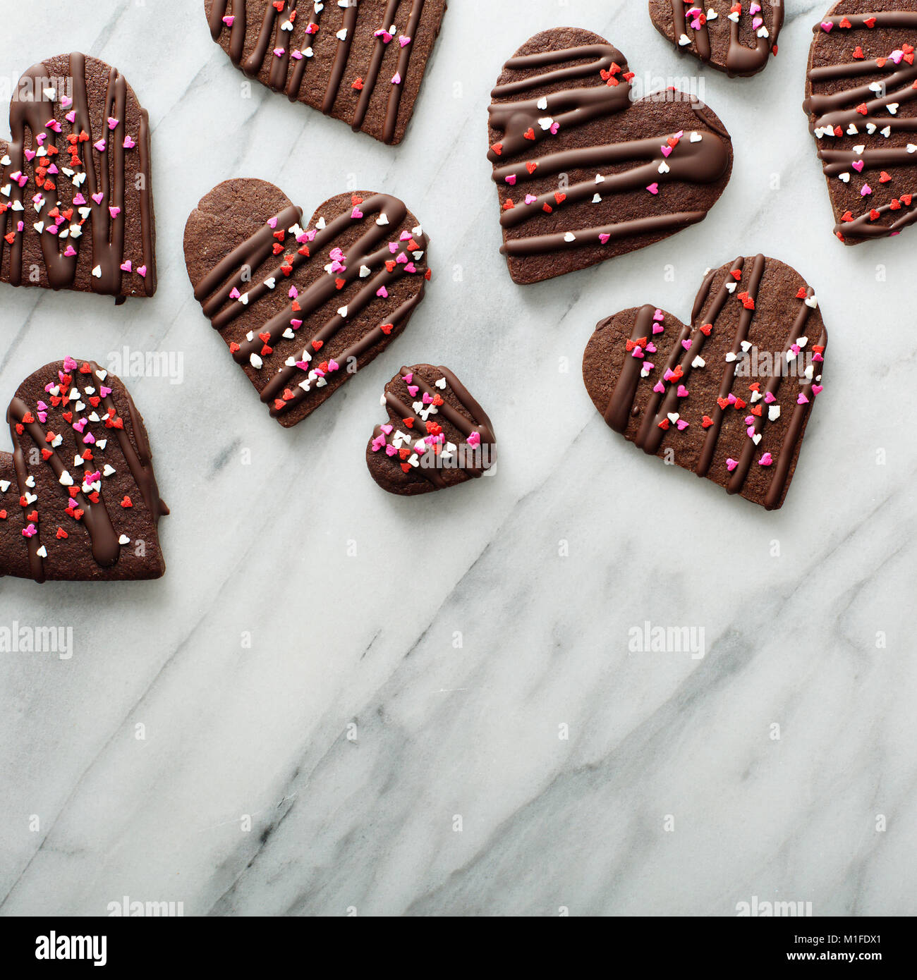Chocolate hearts cookies with sprinkles for Valentines Day on a marble surface with copy space Stock Photo