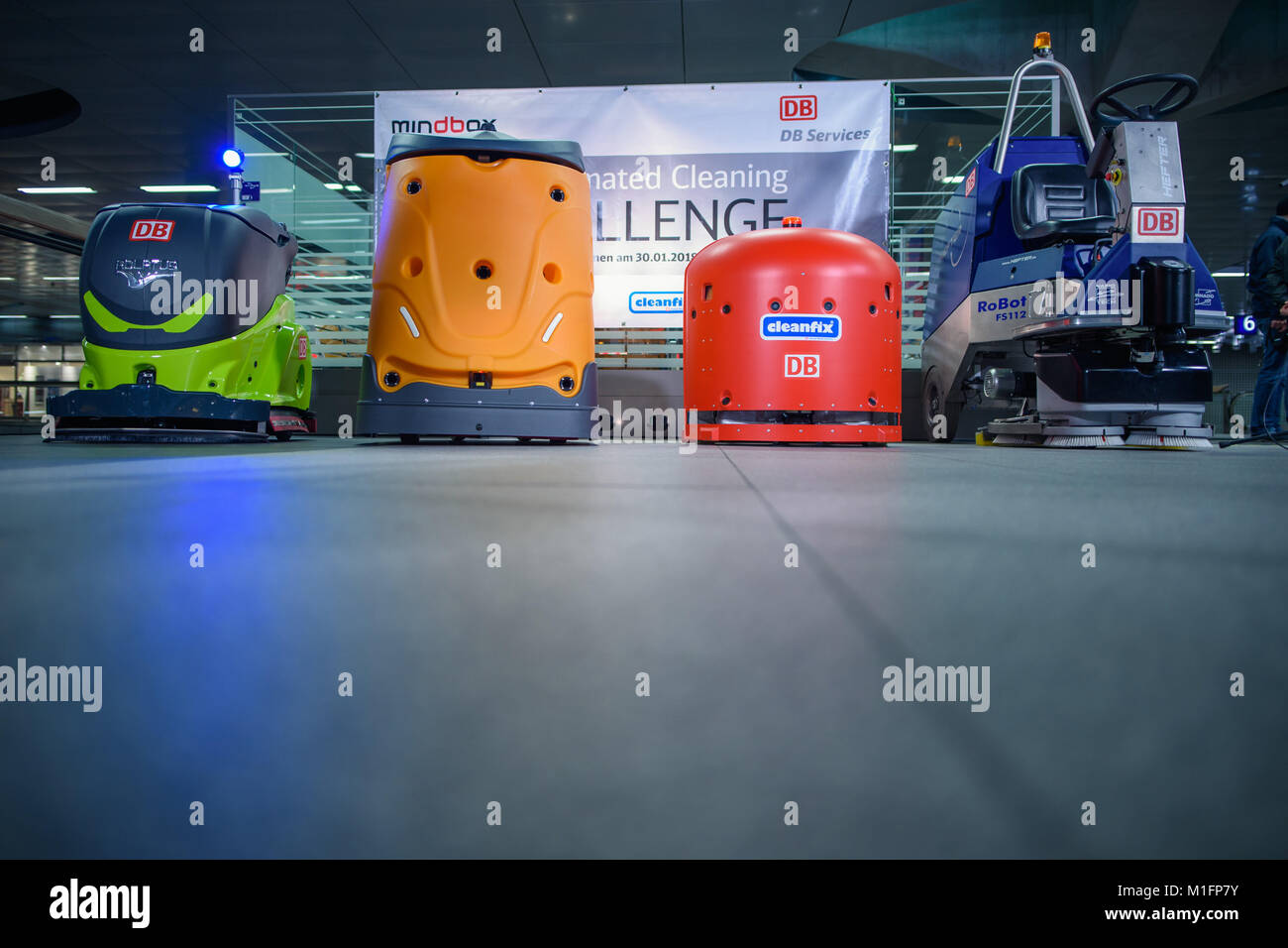 An Adlatus CR700 (L-R), a Taski Swingobot 2000, a Hefter FS112 RoBot and a  Cleanfix RA660 navigator cleaning robot standing in a closed-off area  before a race between four manufacturers of cleaning