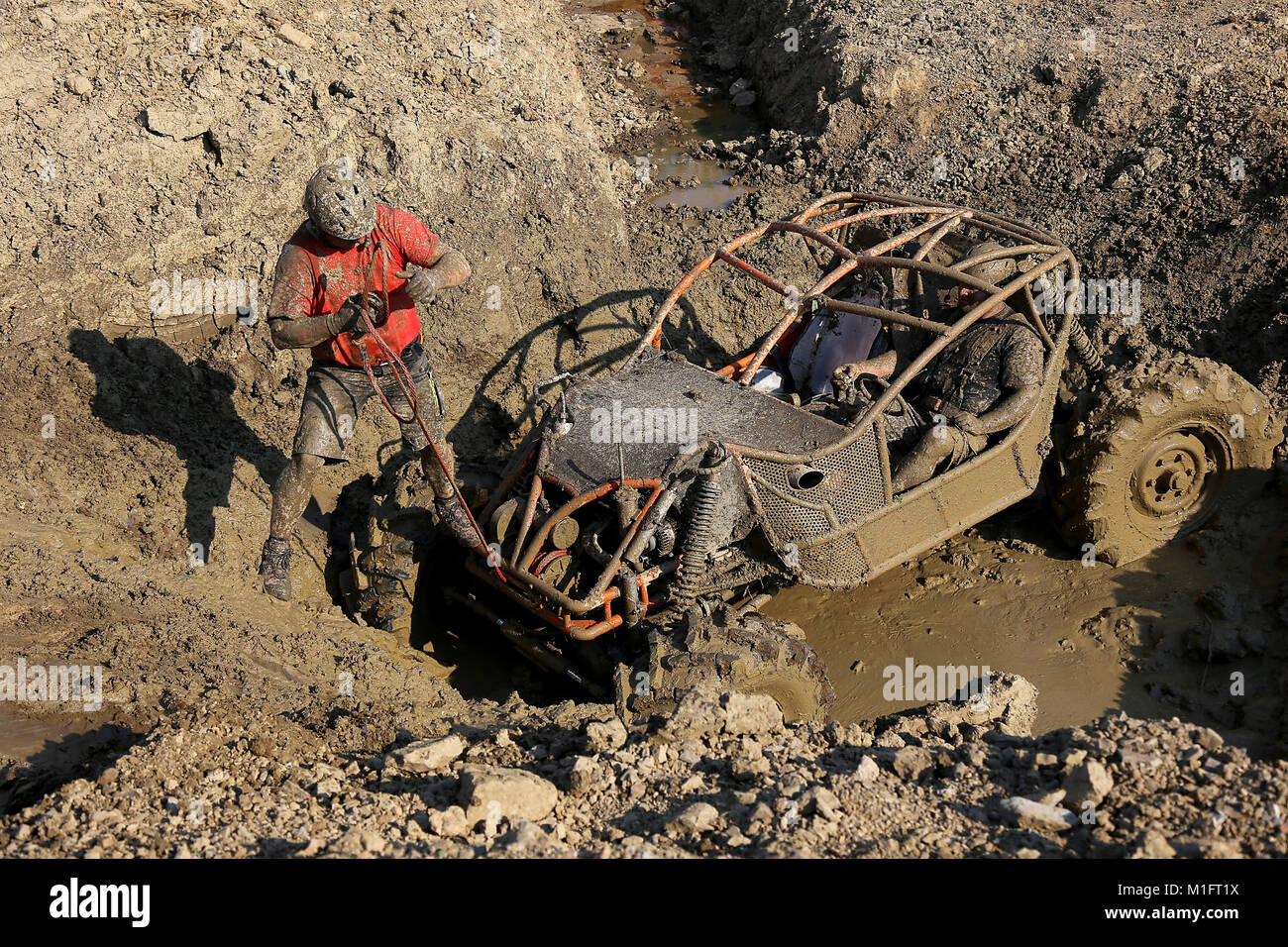 Rence, Slovenia - May 27, 2017: Offroad 4wd race - 4wd vehicle is preparing to scale uphill through mud with car winch. Copilot is pulling the winch. Stock Photo
