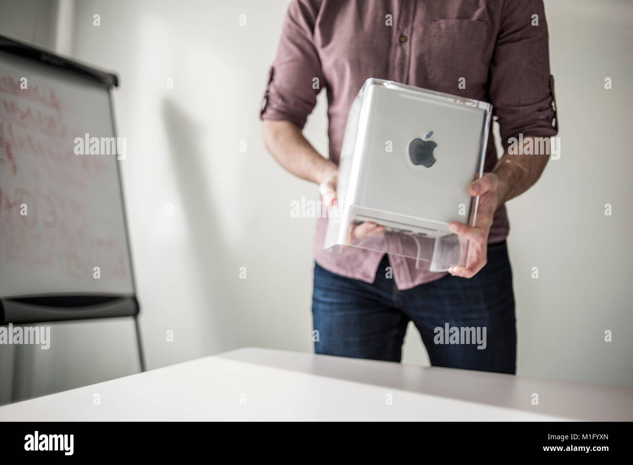 A member of staff shows Power Mac G4 Cube, release date July 2000, at MacPaw's Ukrainian Apple Museum in Kiev, Ukraine on January 26, 2017. Ukrainian developer MacPaw has opened Apple hardware museum at the company’s office in Kiev. The collection has more than 70 original Macintosh models dated from 1981 to 2017. Stock Photo