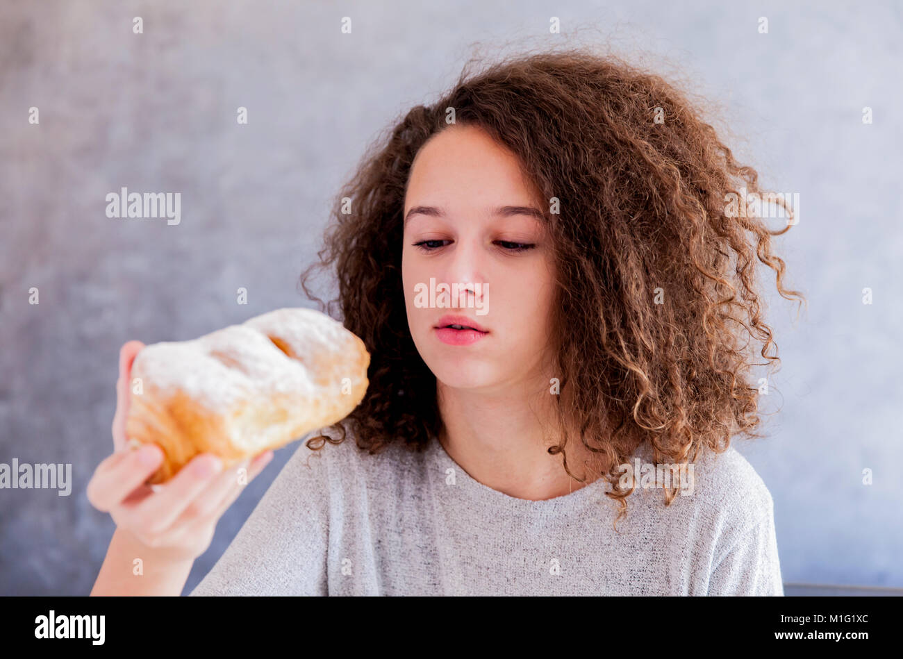 Portrait Of Curly Hair Teen Girl Eating Croissant Stock Photo