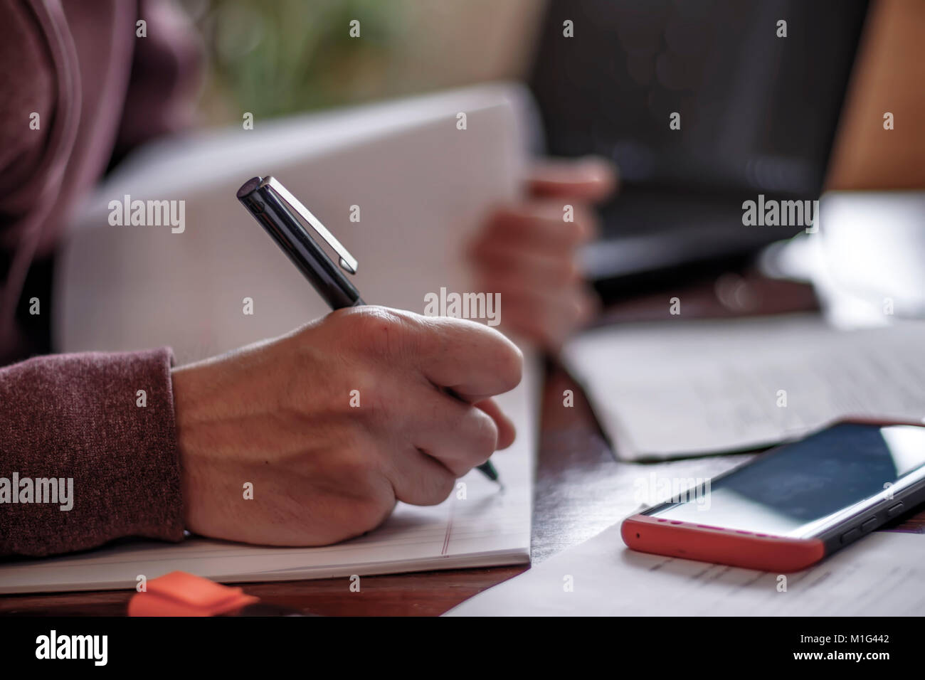 The hand of a man with a pen writing in a notebook Stock Photo - Alamy