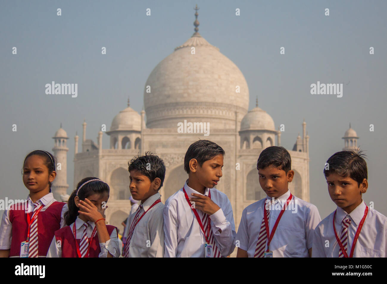 Indian school children looking bored and fed up at a trip to the Taj Mahal in Agra, Utter Pradesh, India, in red and white school uniforms Stock Photo