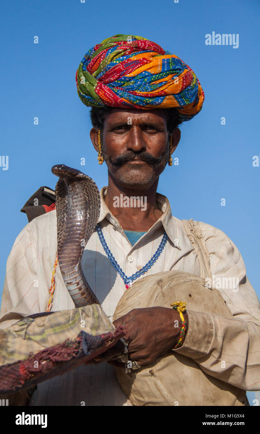 Snake charmer with a cobra to entertain tourists for money at the Pushkar Camel Fair, Rajasthan, India Stock Photo