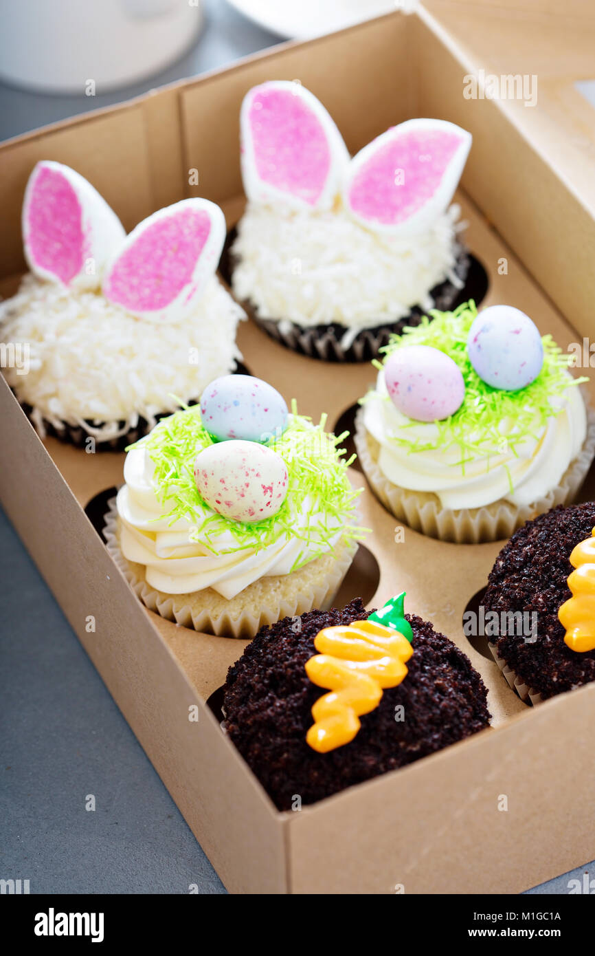 Assortment of easter cupcakes in a box with bunny ears and candy eggs