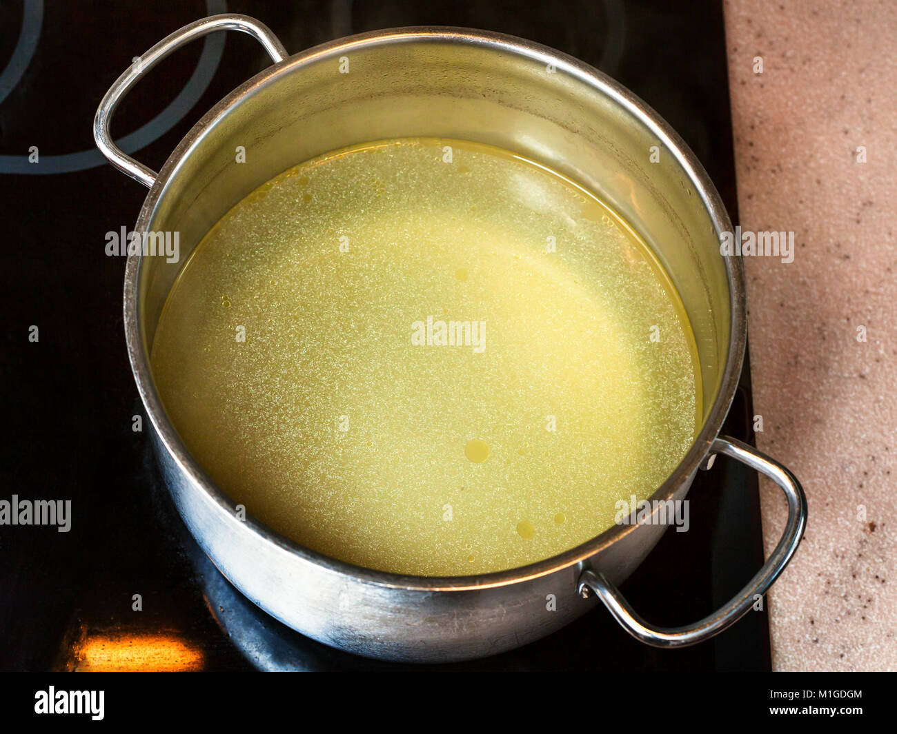cooking soup - clear fat beef bouillon in steel stockpot on ceramic cooker Stock Photo