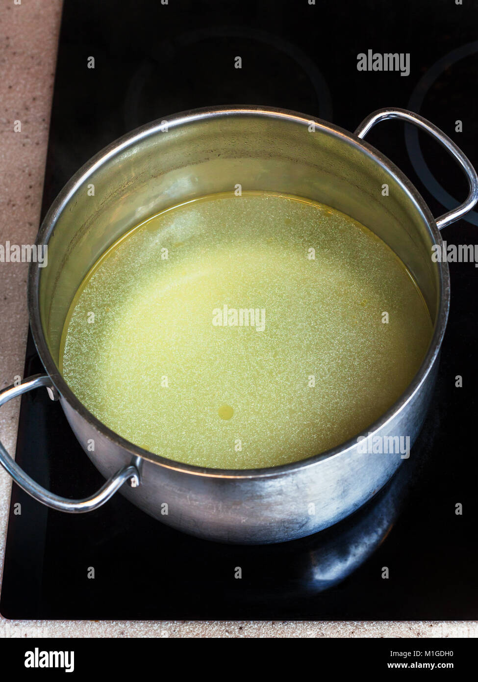 cooking soup - clear fat meat bouillon in steel stockpot on ceramic cooker Stock Photo