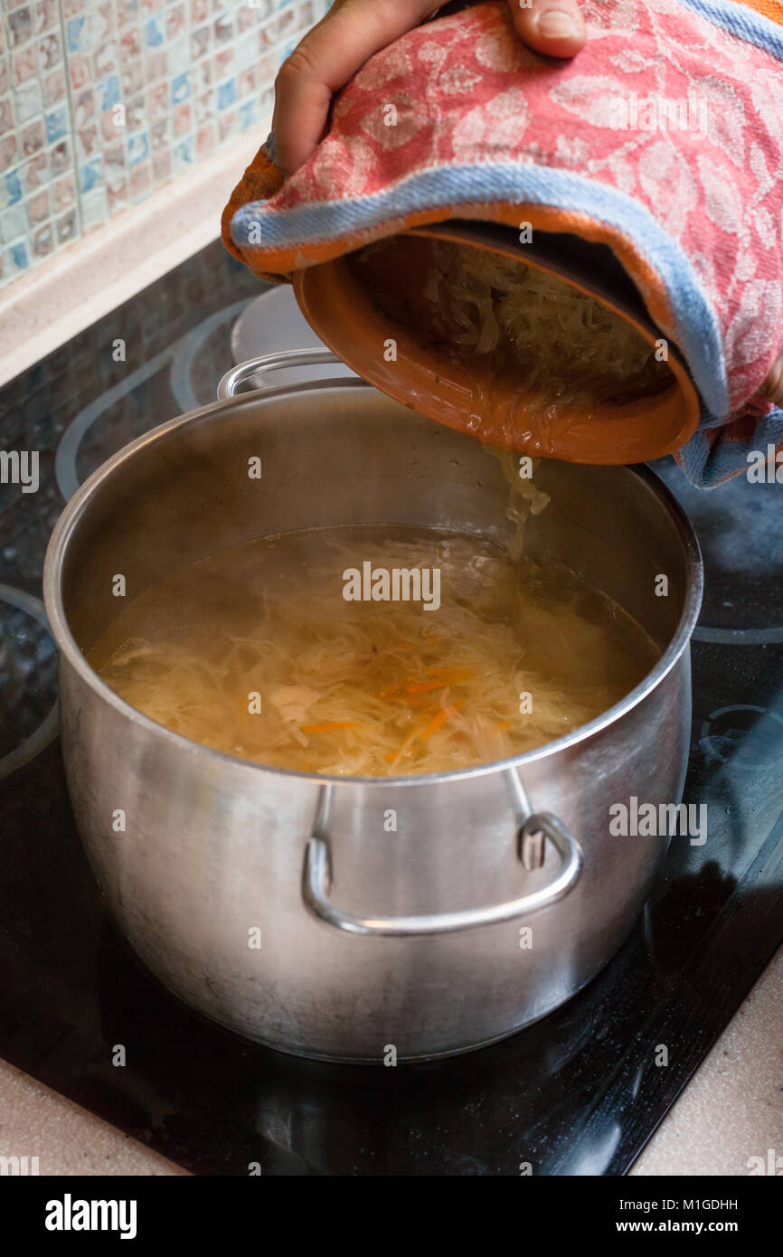cooking soup the cook puts stewed sauerkraut from ceramic pot into