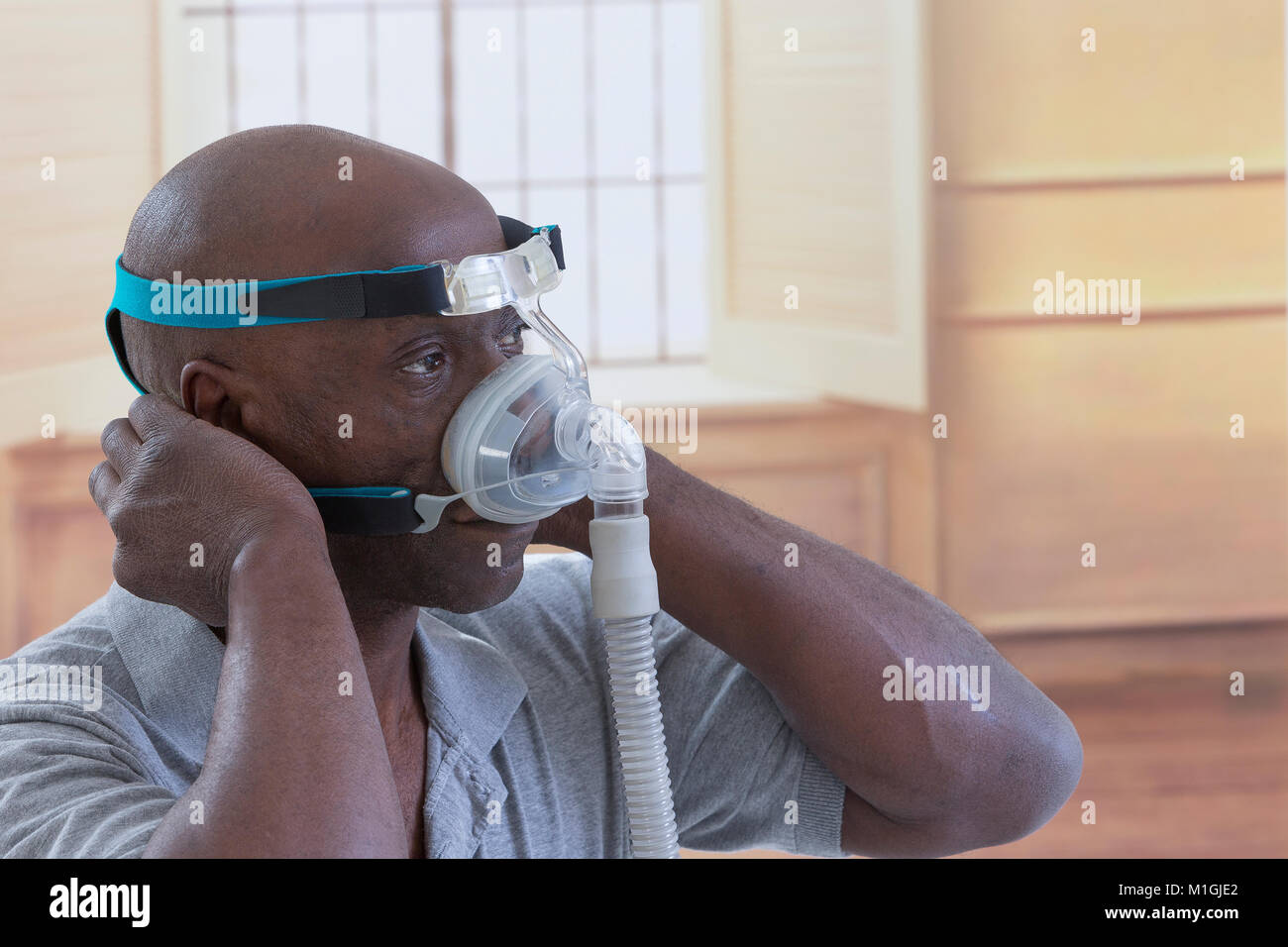 Man with a sleeping disorder tries on a Cpap for the first time,Man learns to adjust his CPAP equipment in luxery house beroom Stock Photo