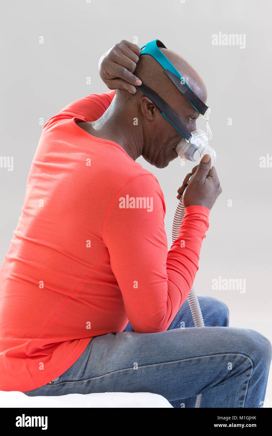 Man with a sleeping disorder tries on a Cpap for the first time,Man learns to adjust his CPAP equipment on white background Stock Photo