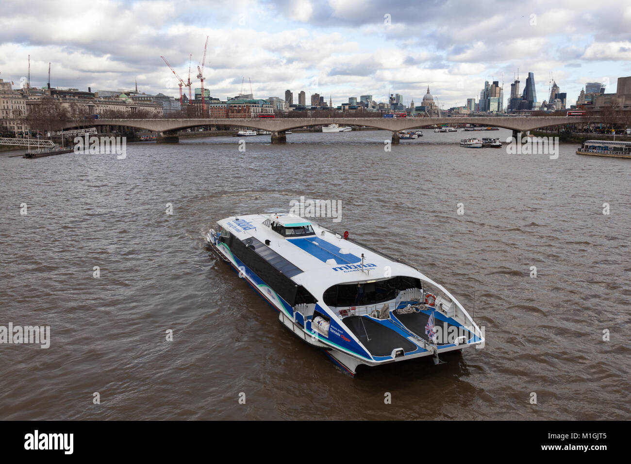 A sight-seeing boat on the River Thames with Waterloo Bridge, St Paul's Cathedral and the skyscrapers of the City's financial district behind. London, Stock Photo