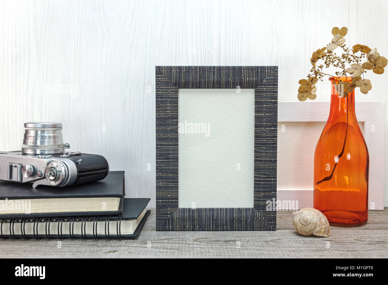 classic film camera, photo frame and red glass vase with dried flowers on wooden boards background Stock Photo