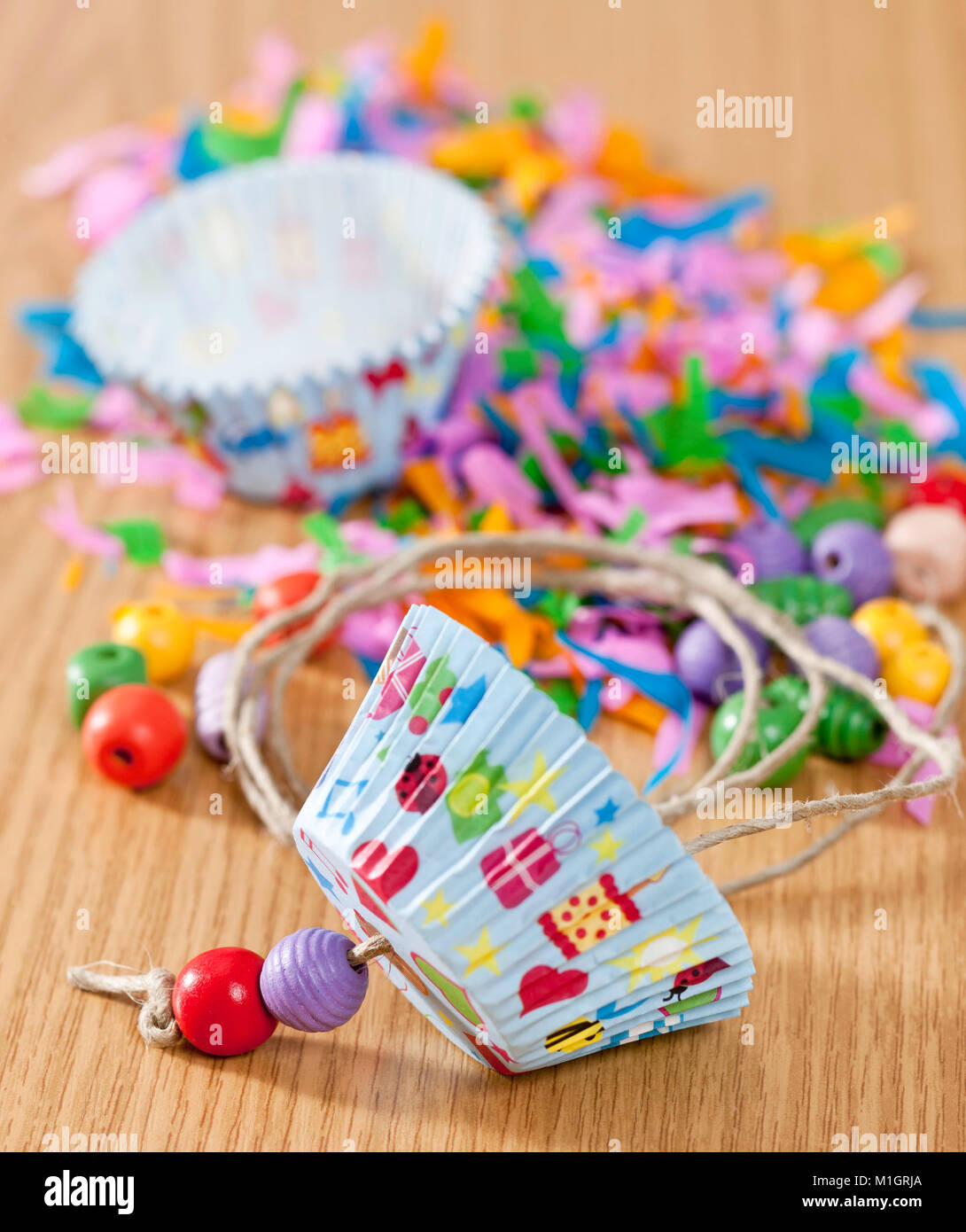 Budgerigar, Budgie (Melopsittacus undulatus). Assembly instruction for budgeriar toy, made from paper muffin liners and wooden beads . German Stock Photo