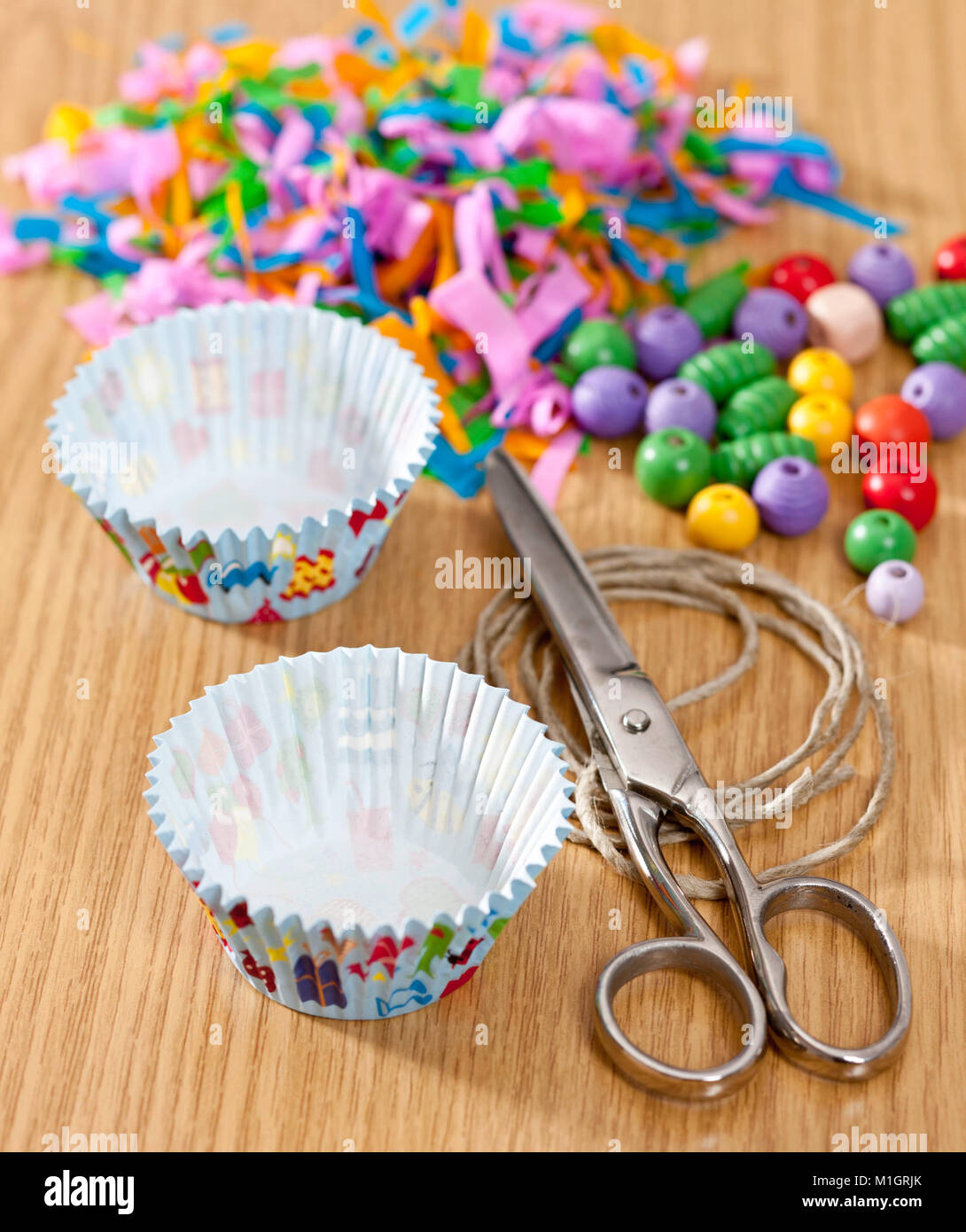 Budgerigar, Budgie (Melopsittacus undulatus). Assembly instruction for budgeriar toy, made from paper muffin liners and wooden beads . German Stock Photo