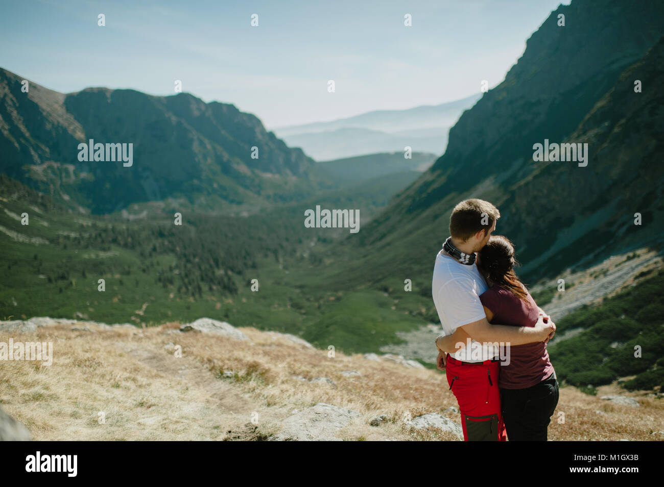 Man and woman hugging and looking into a green forest valley of the ...