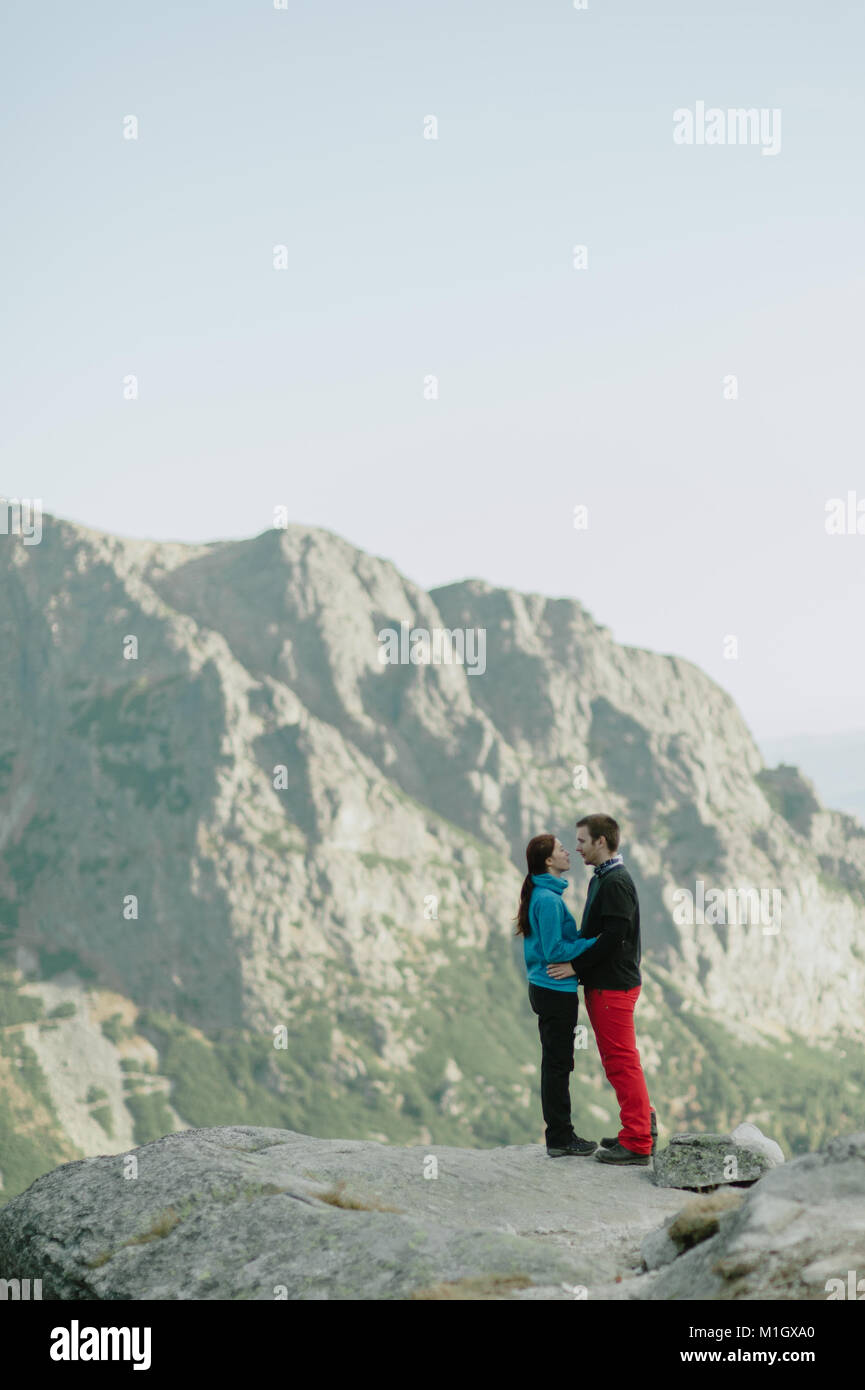 Man and woman in love hugging on top of mountains and looking into each ...