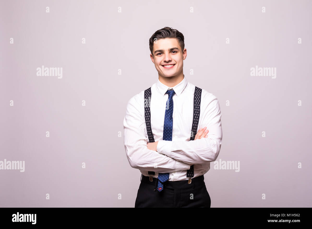 Portrait of happy smiling young man wearing a white shirt standing with ...