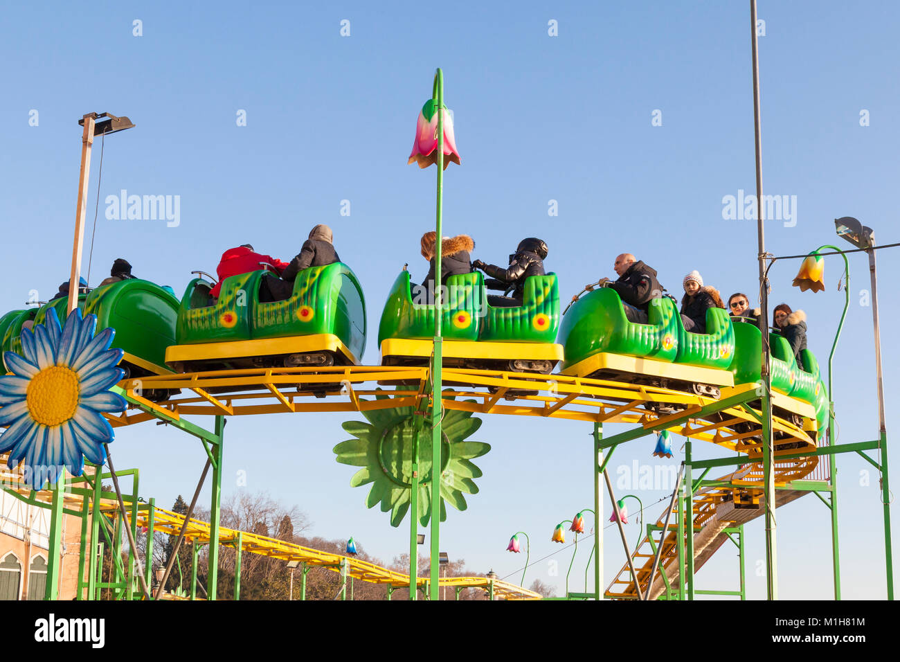 Group of young kids with their parents riding on a Wacky Worm roller coaster  in Venice, Italy against a blue sky showing the track during a seasonal w  Stock Photo - Alamy