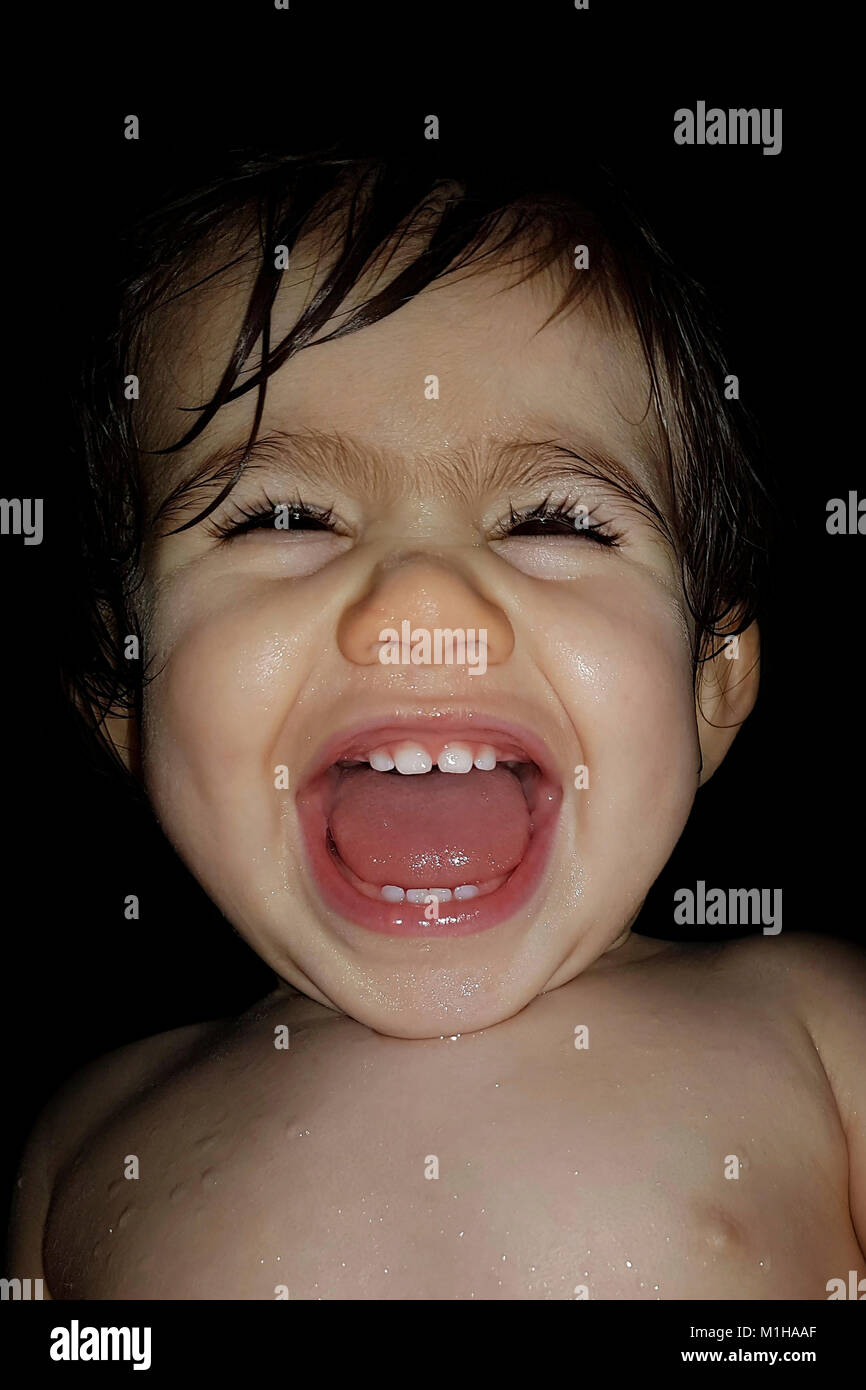 A 1-year-old little girl roaring with laughter at the time of her bath. Laughing baby. LOL Stock Photo