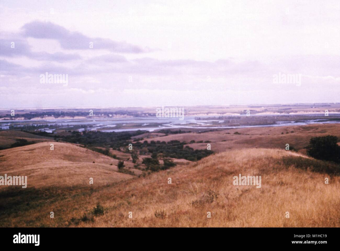 Photograph of Lewis and Clark Lake, a gray sky in the background, grassy cliffs in the