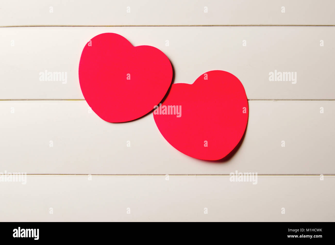two red paper hearts on a light striped background Stock Photo