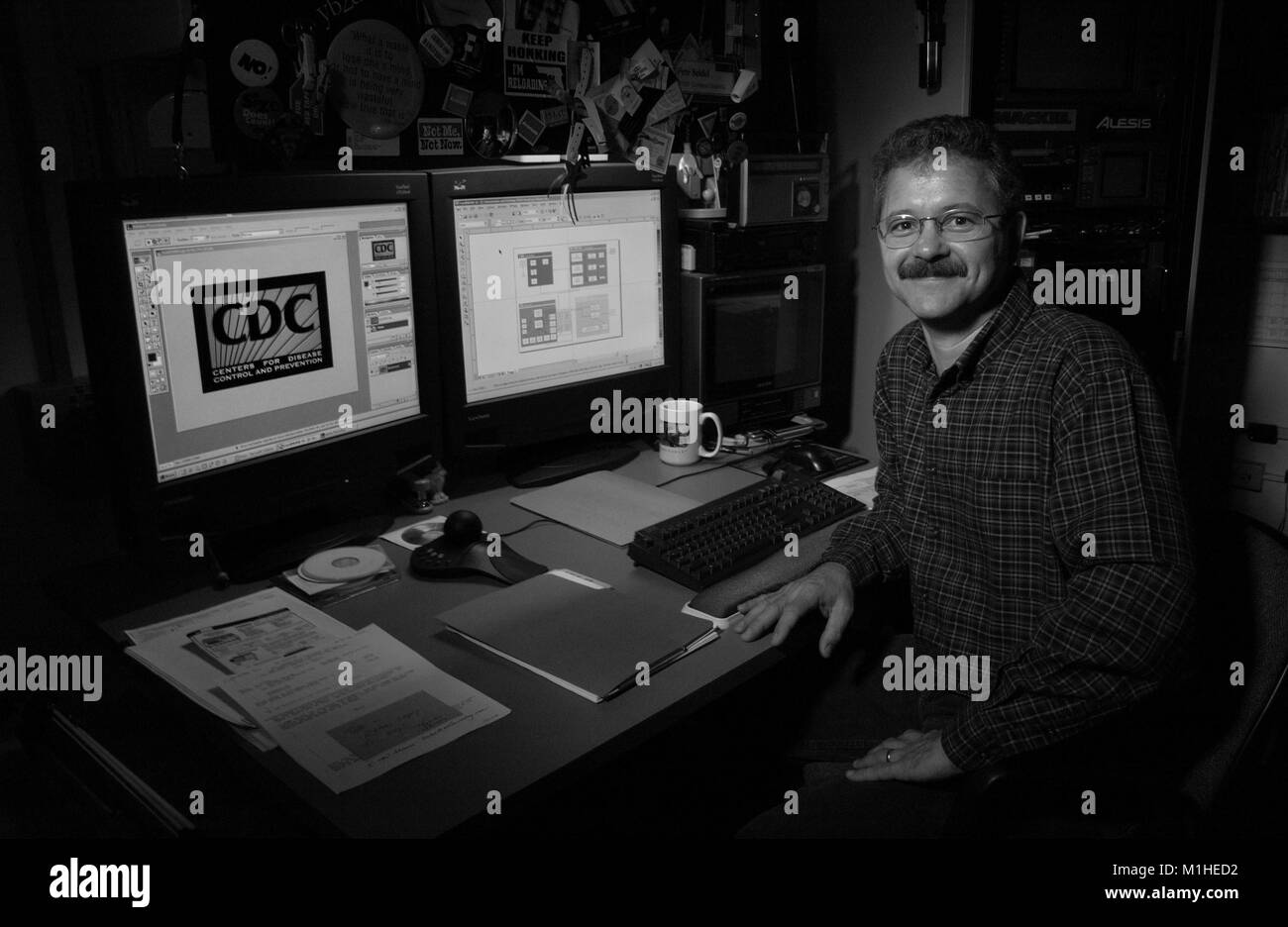 Photograph of Pete Seidel, computer graphics specialist at the CDC (Acting Branch Chief for the Division of Specialized Media), posing next to his desk, where he works on the visual part of the CDC presentation at the 131st annual APHA (American Public Health Association) Meeting, 2003. Image courtesy CDC. () Stock Photo