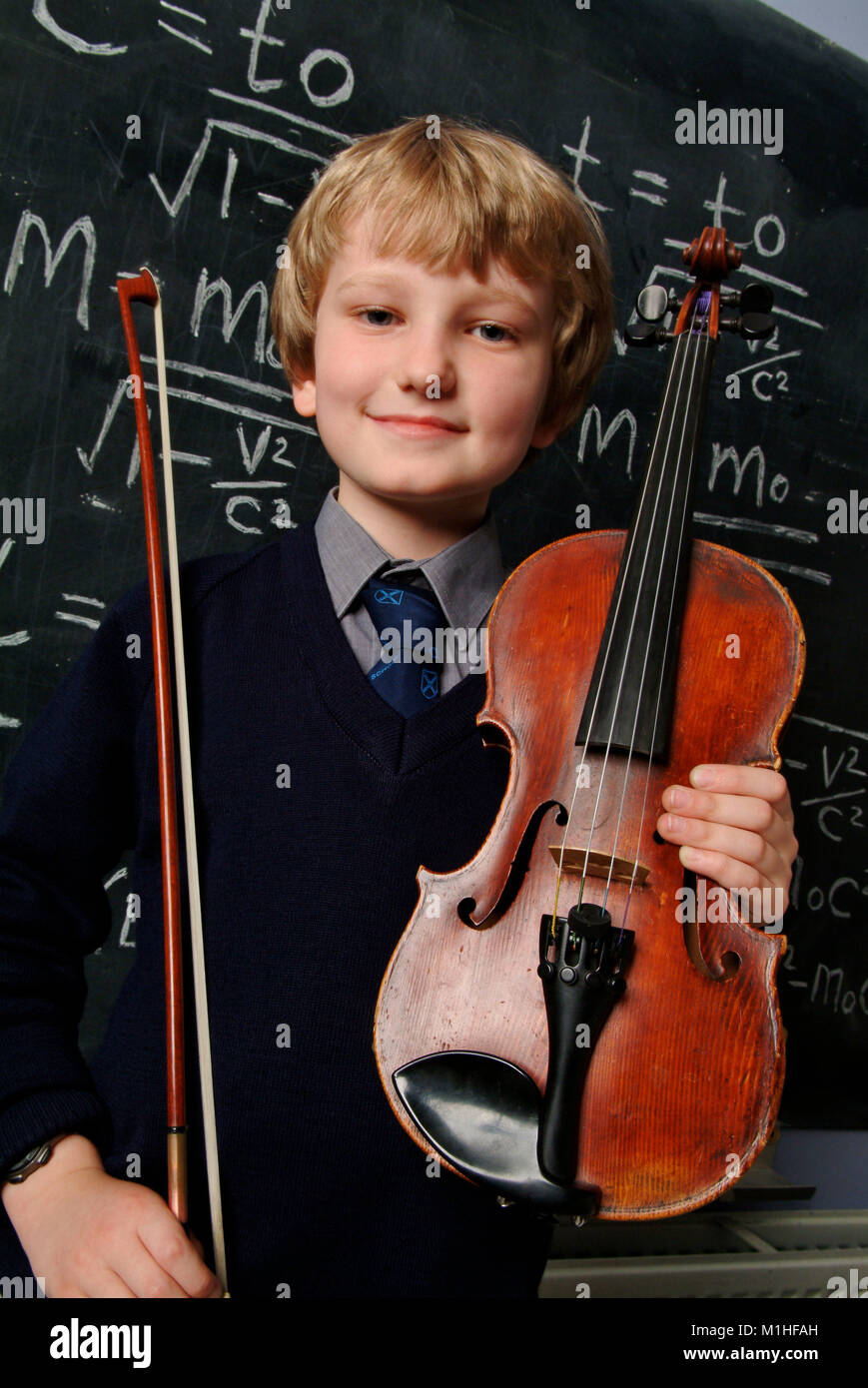 A young male school student who is an accomplished violin player and mathematician, seen in front of a blackboard, equasion and Albert Einstein photo Stock Photo