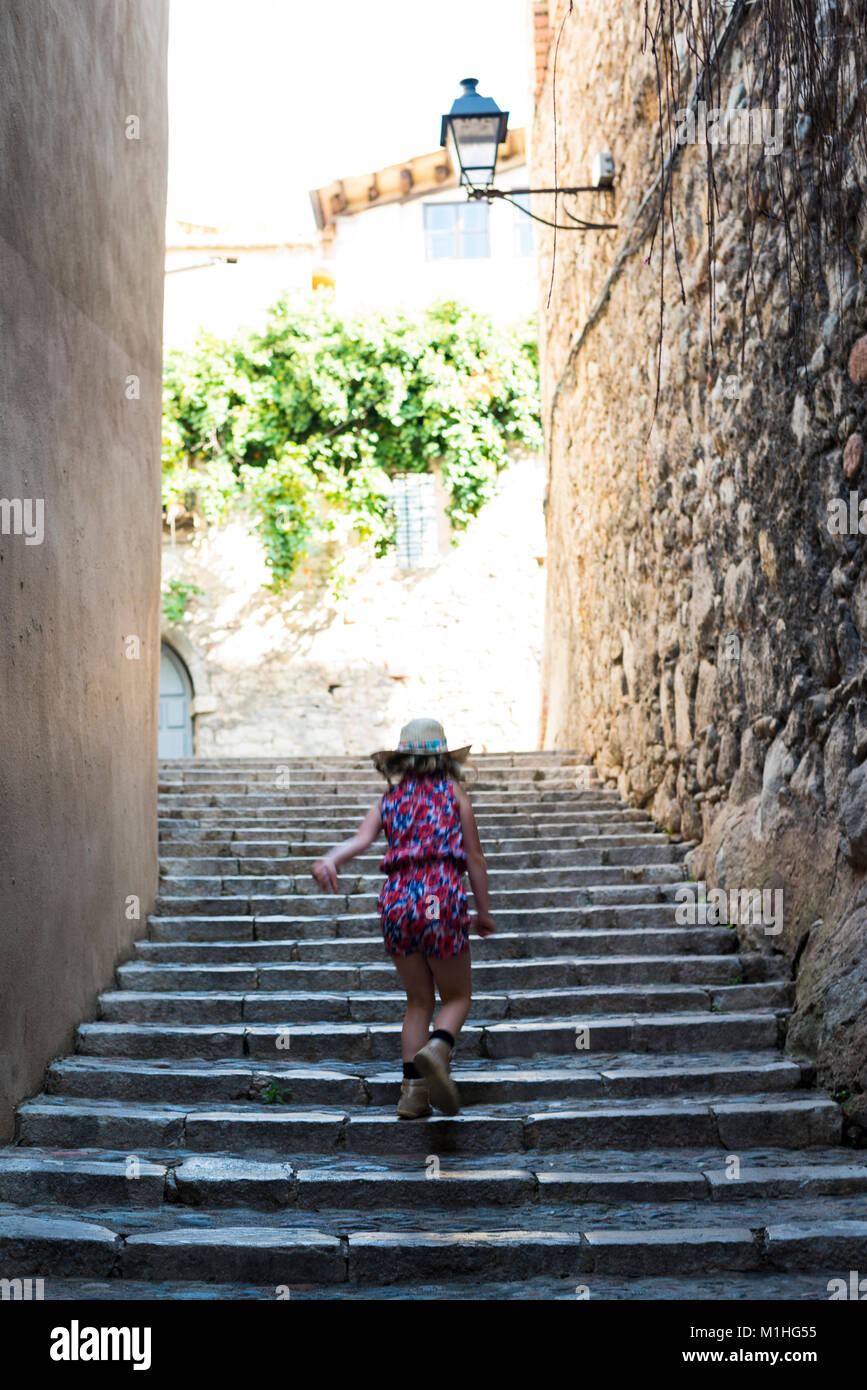 Girl walking up steps, exploring the city of Girona, Spain while on holiday Stock Photo