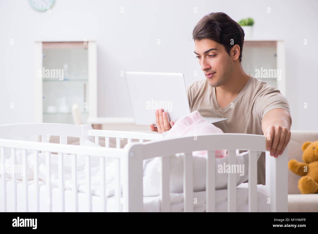 Young dad student preparing for exams and looking after baby Stock