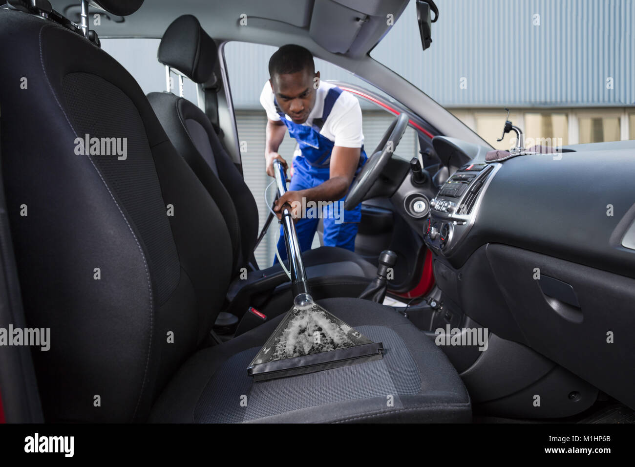Young Handyman Vacuuming Car Front Seat With Vacuum Cleaner Stock Photo