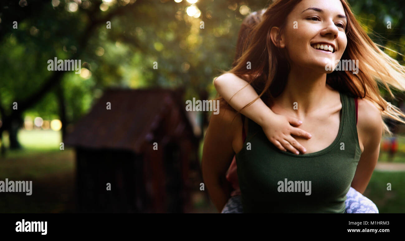 Portrait of young woman carrying little kid on her back Stock Photo