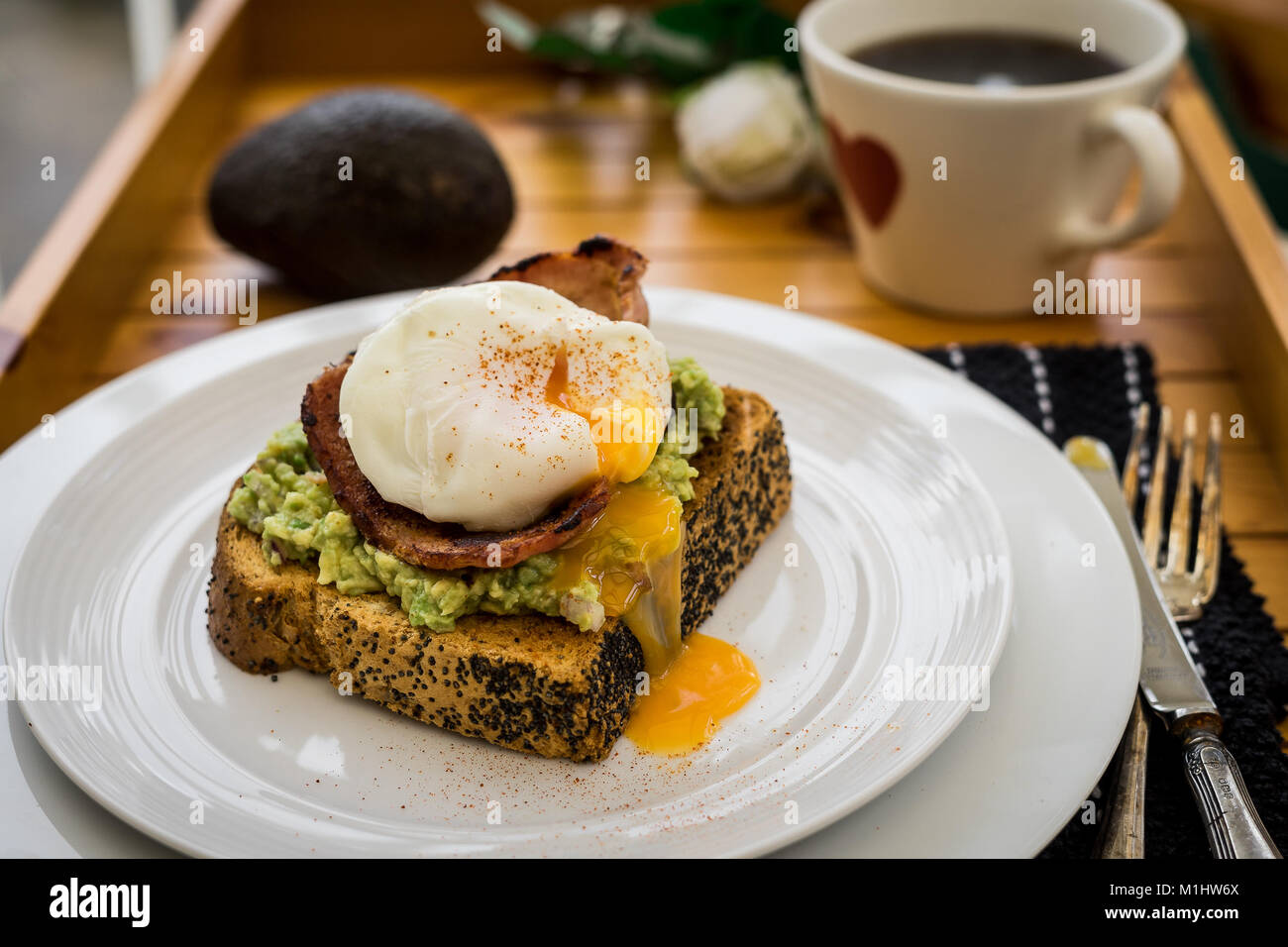 Smashed Avocado with bacon and a poached egg Stock Photo