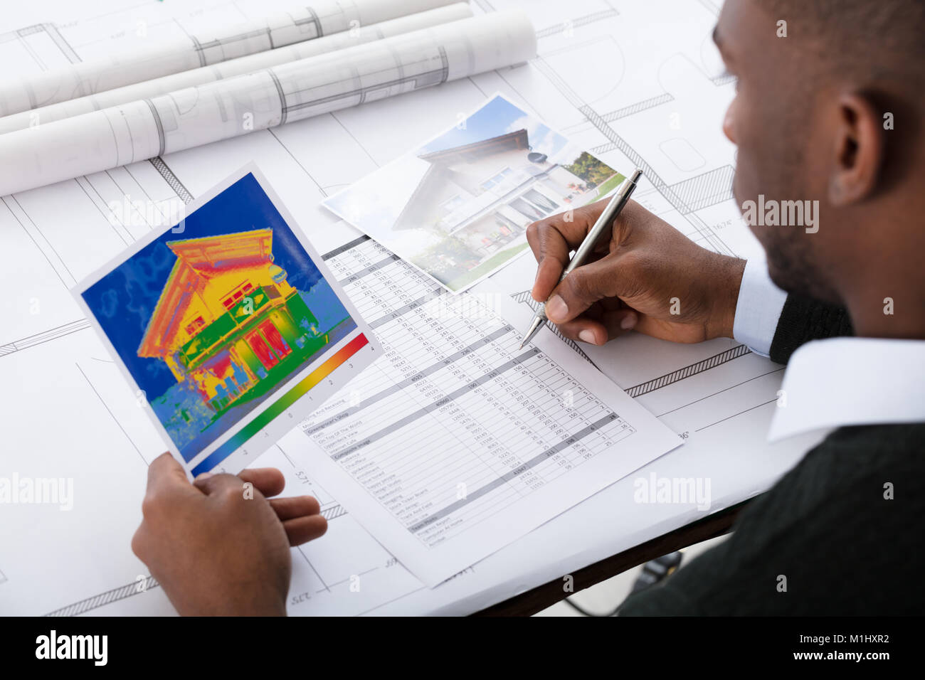 Close-up Of An Architect Calculating Heat Temperature Against Blue Print Stock Photo