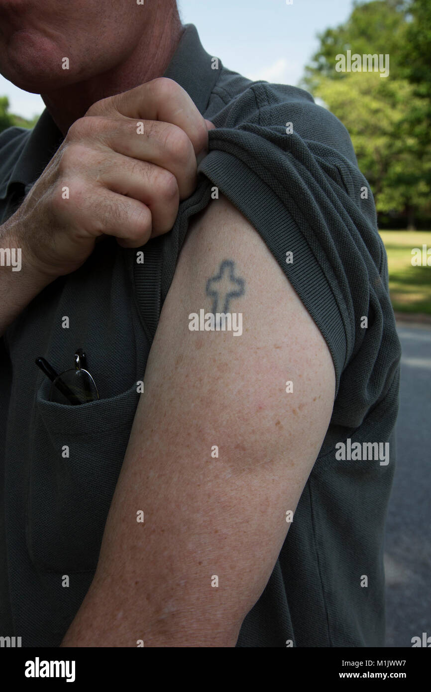 Man Showing his Cross Tattoo on Arm Stock Photo