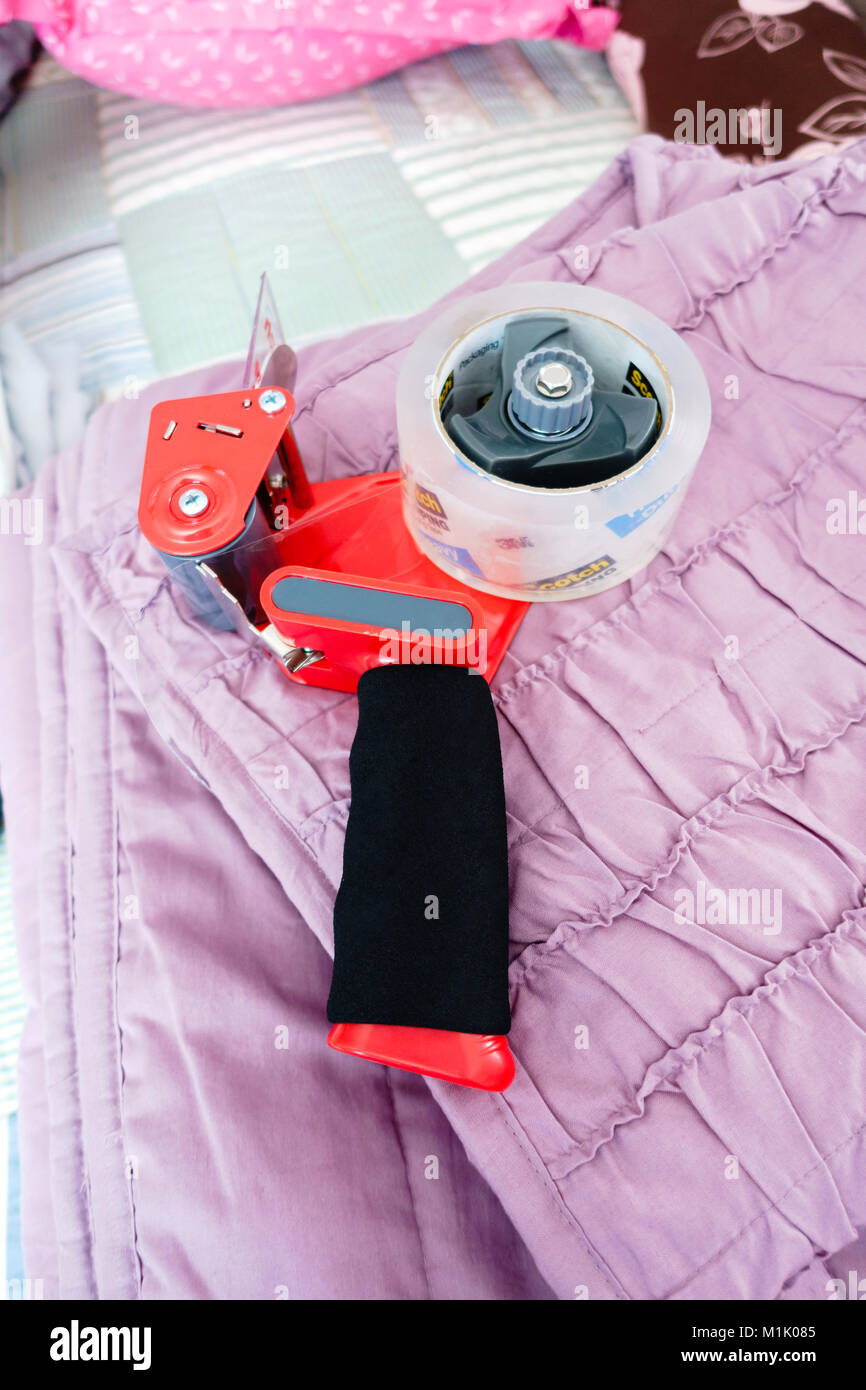 A tape dispenser holding boxing tape lying on a folded bedspread to be packed up to move. USA. Stock Photo
